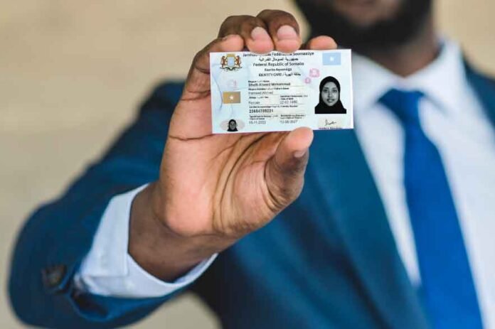 Man holding Somali National ID with face partially hidden